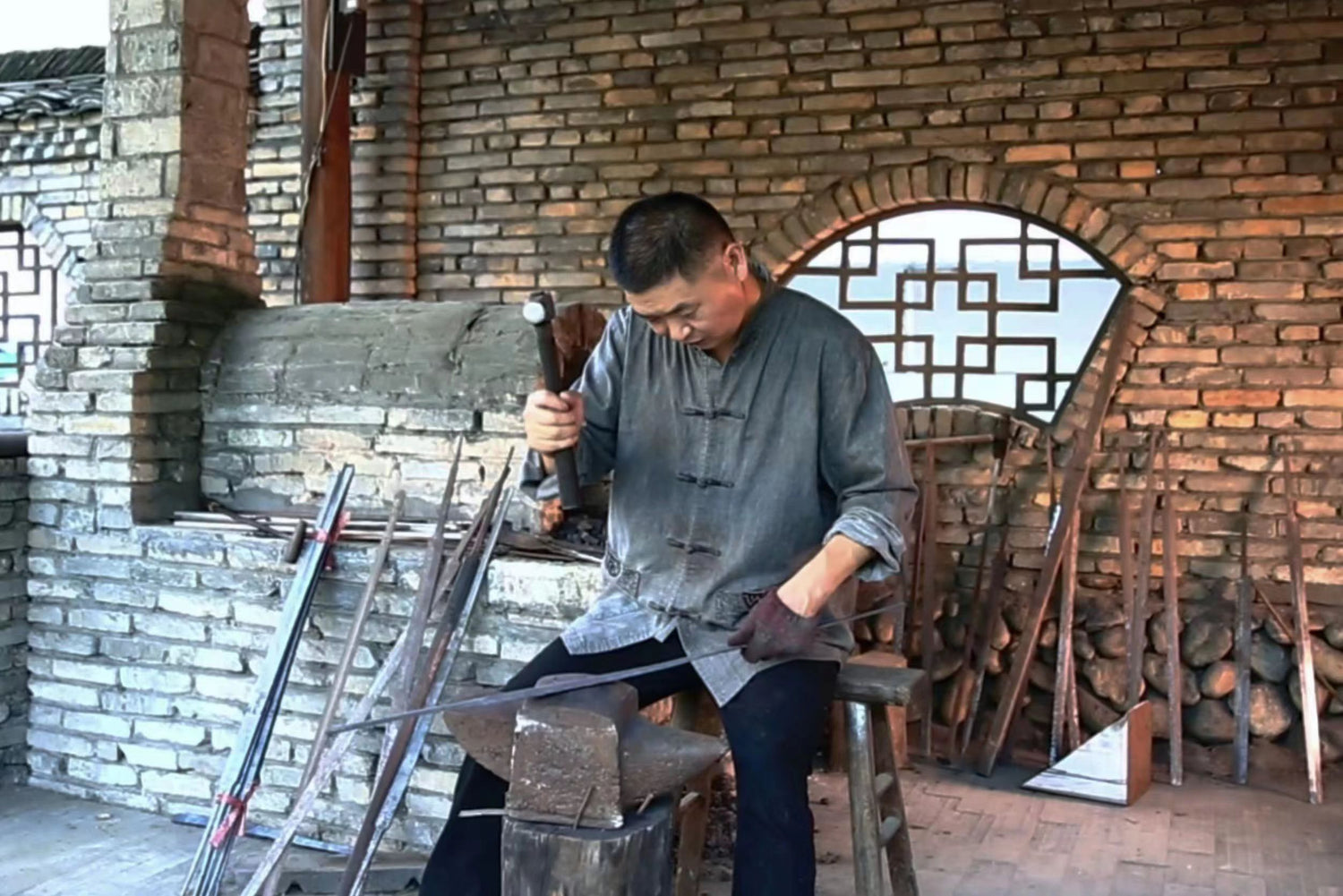 Man working with tools on an anvil in a workshop setting.