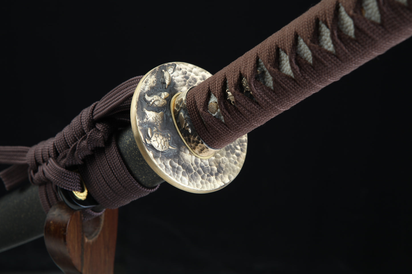 Close-up of a sword with a decorative hilt wrap on a black background