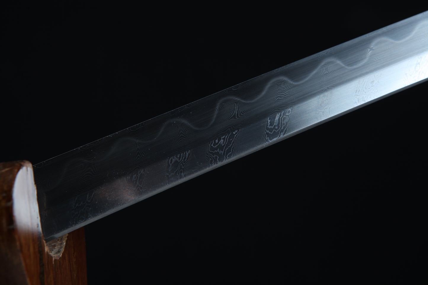 Close-up of a sword blade with engraved patterns on a black background