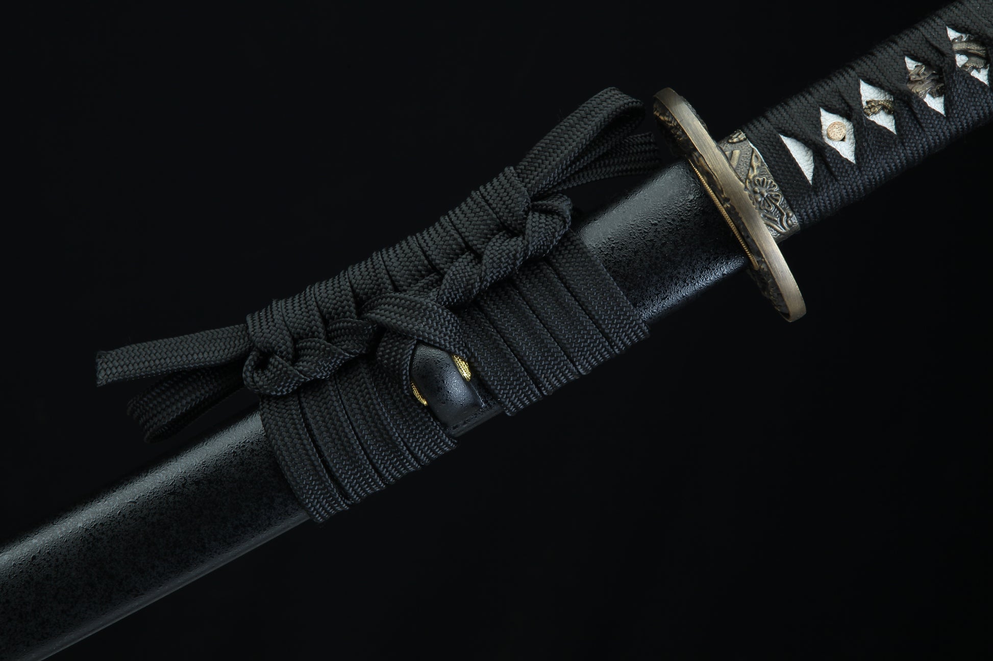 Black sword with decorative hilt on a black background