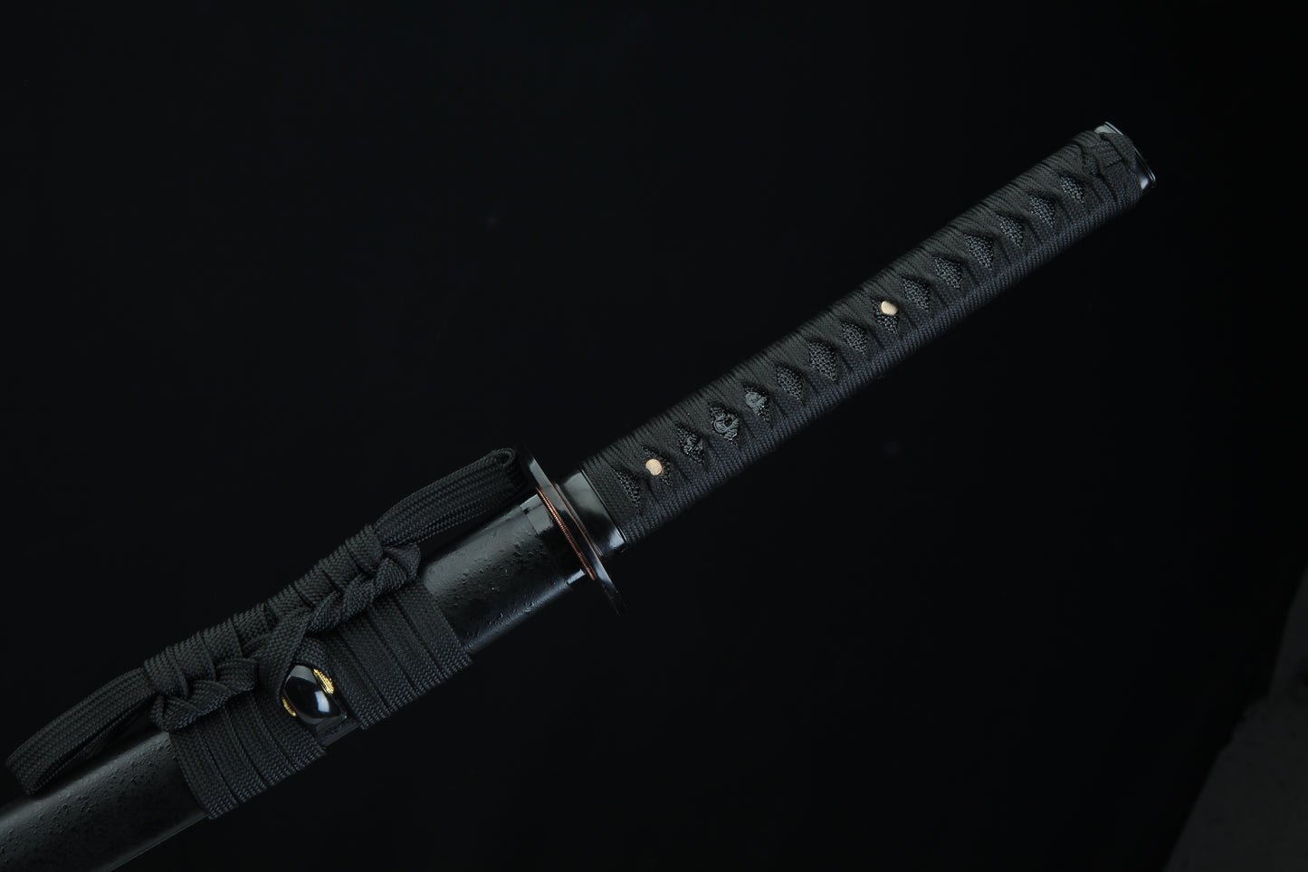 Black sword with textured handle on a black background