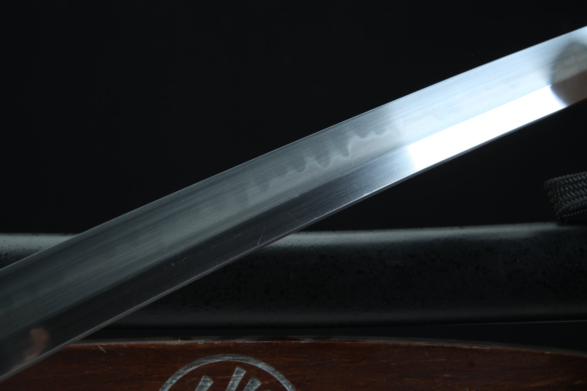 Close-up of a sword blade with engraved text on a dark background