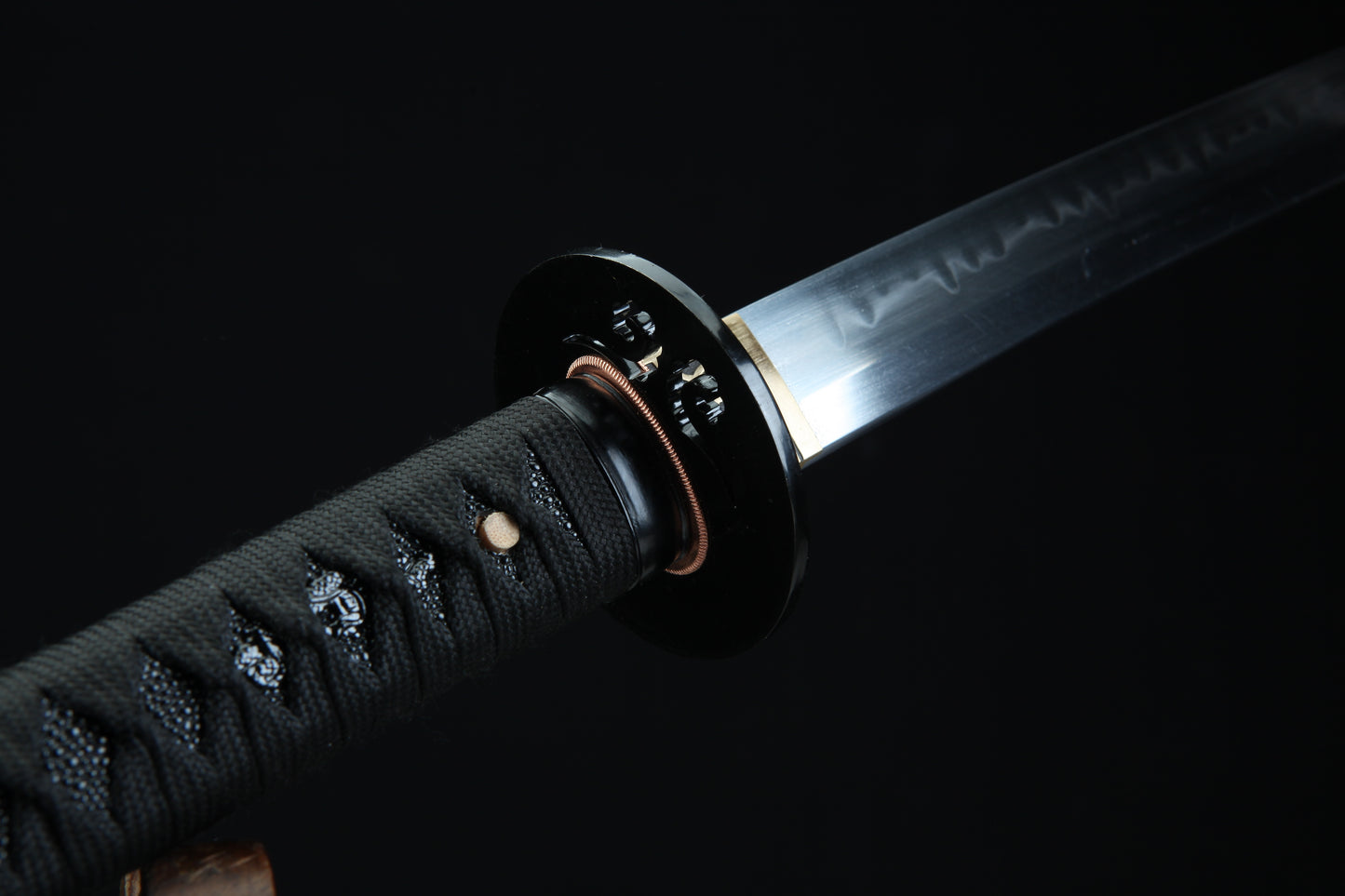 Close-up of a Japanese sword with a black sheath on a dark background
