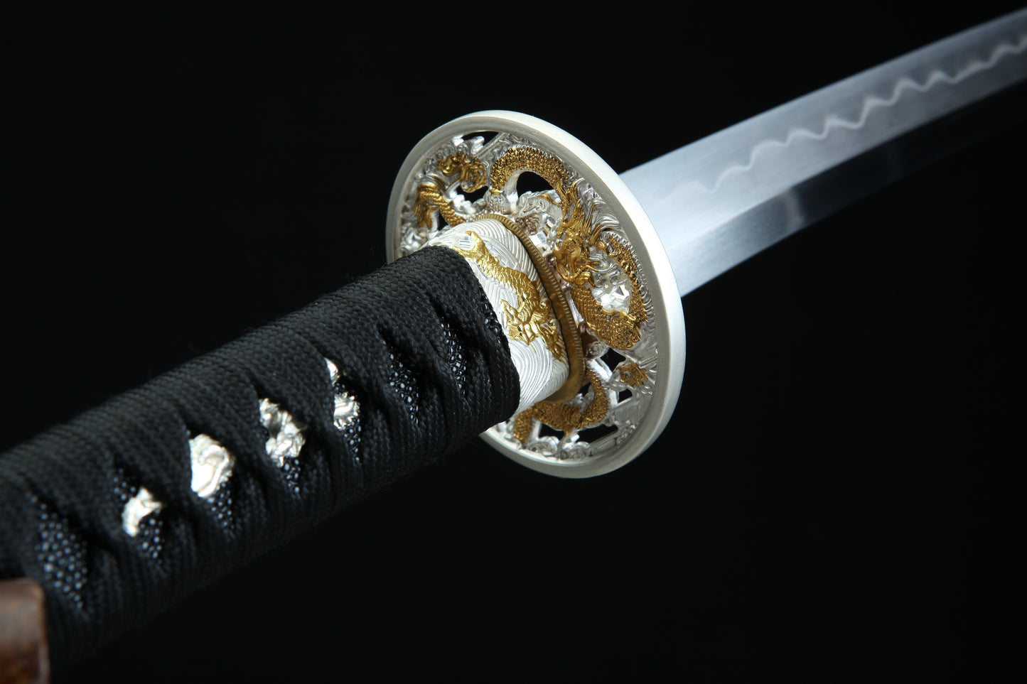Close-up of a sword with decorative hilt on a black background