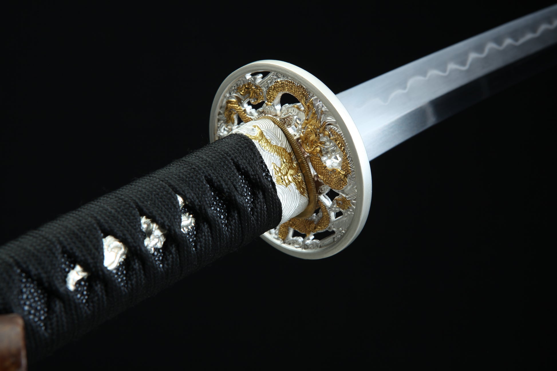 Close-up of a sword with decorative hilt on a black background