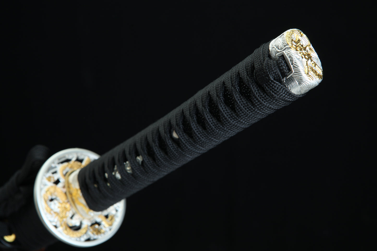 Close-up of a black sword handle with gold decorative elements on a black background