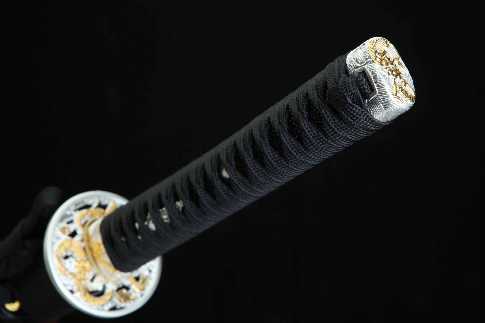 Close-up of a black sword handle with gold decorative elements on a black background