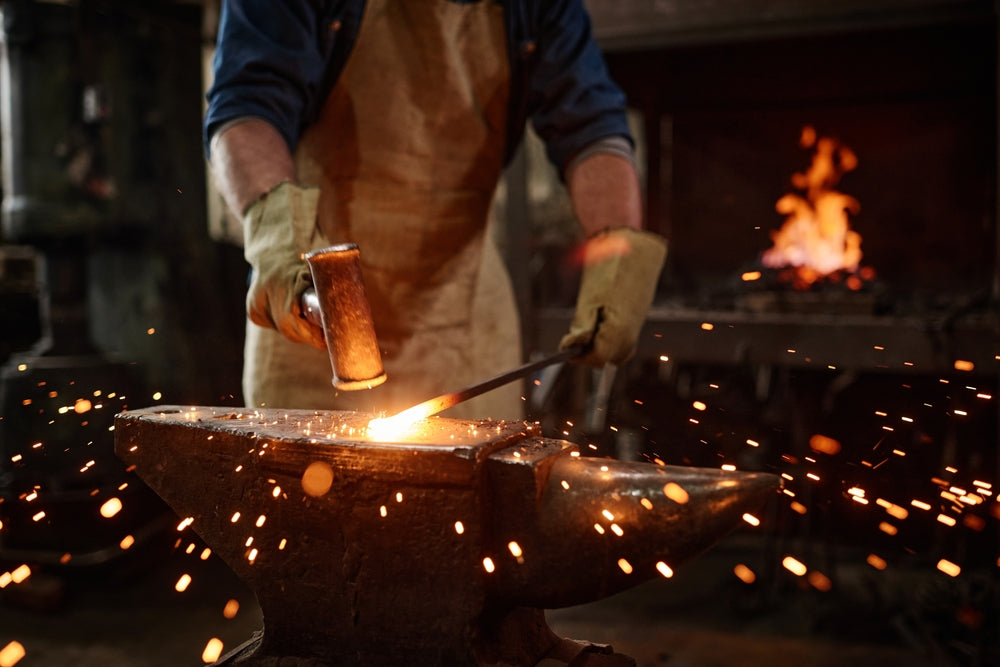 Person working with hot metal in a forge with sparks flying