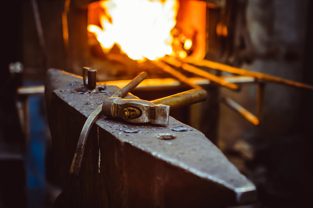 Hammer on an anvil with flames in the background