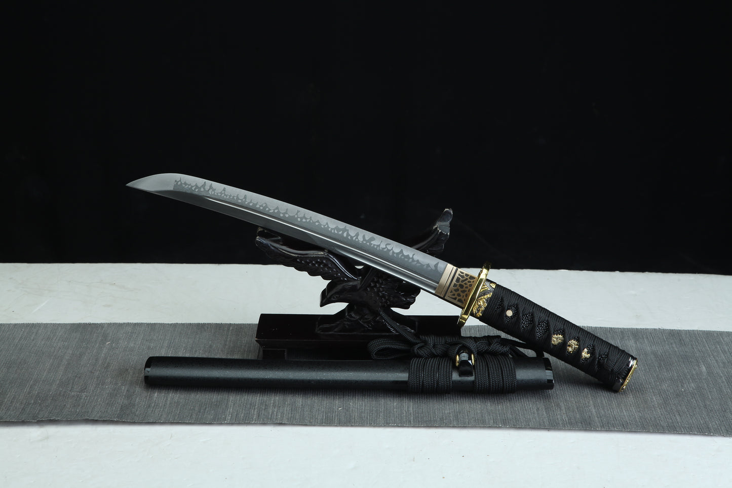 Sword with sheath on a black and white striped surface