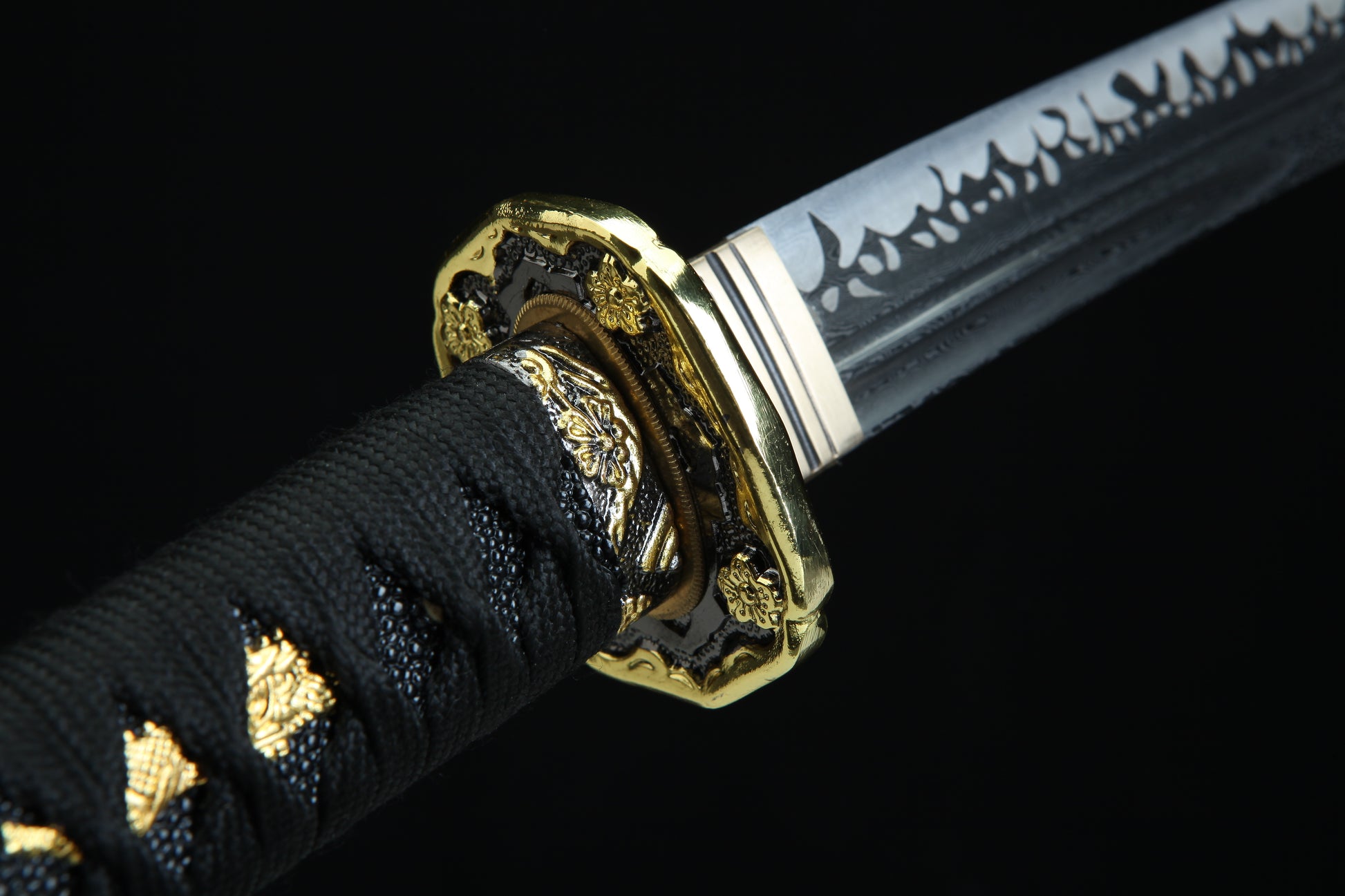 Close-up of a sword with a gold handle on a black background