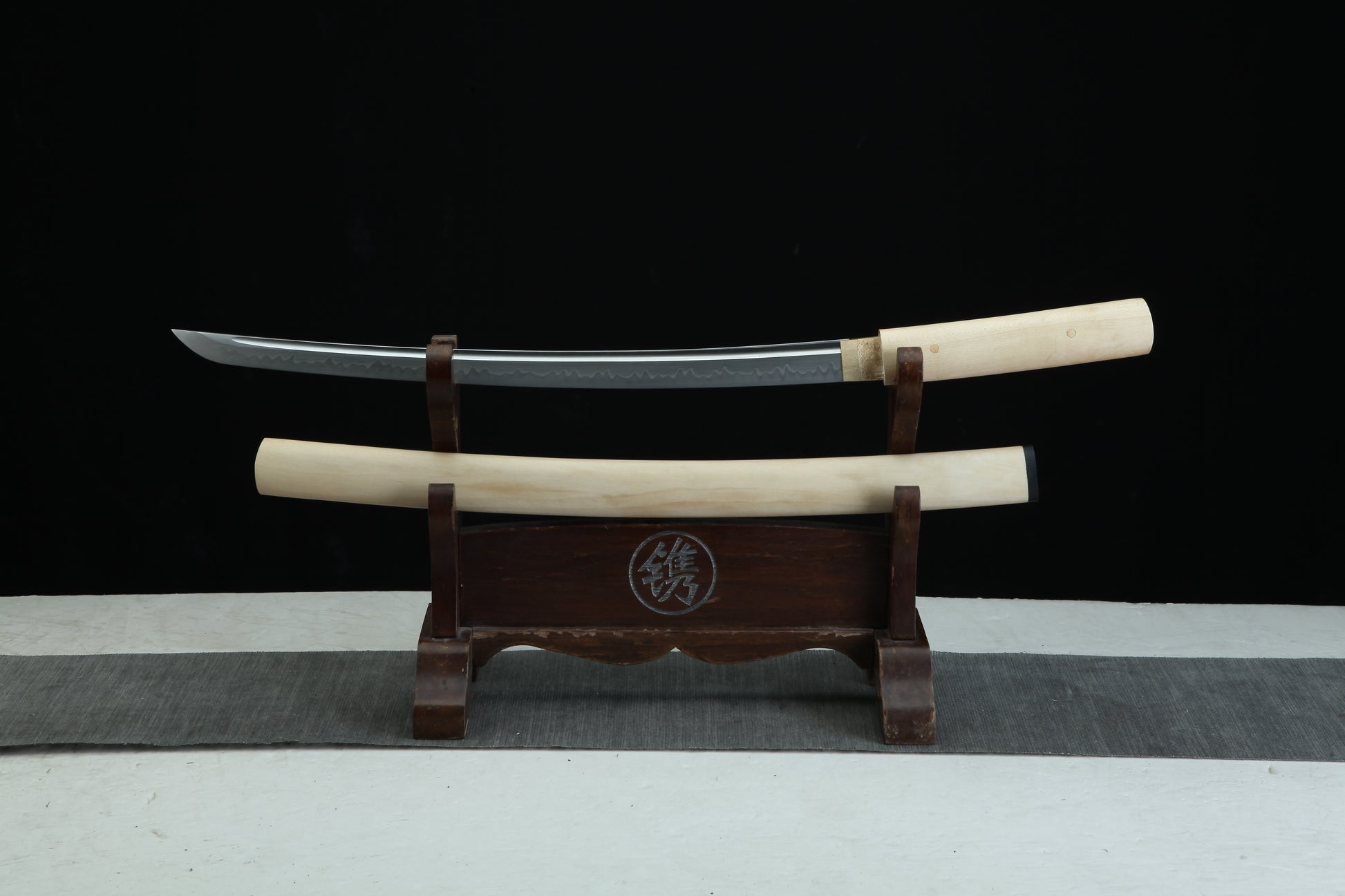 Two swords on a wooden stand with a black background