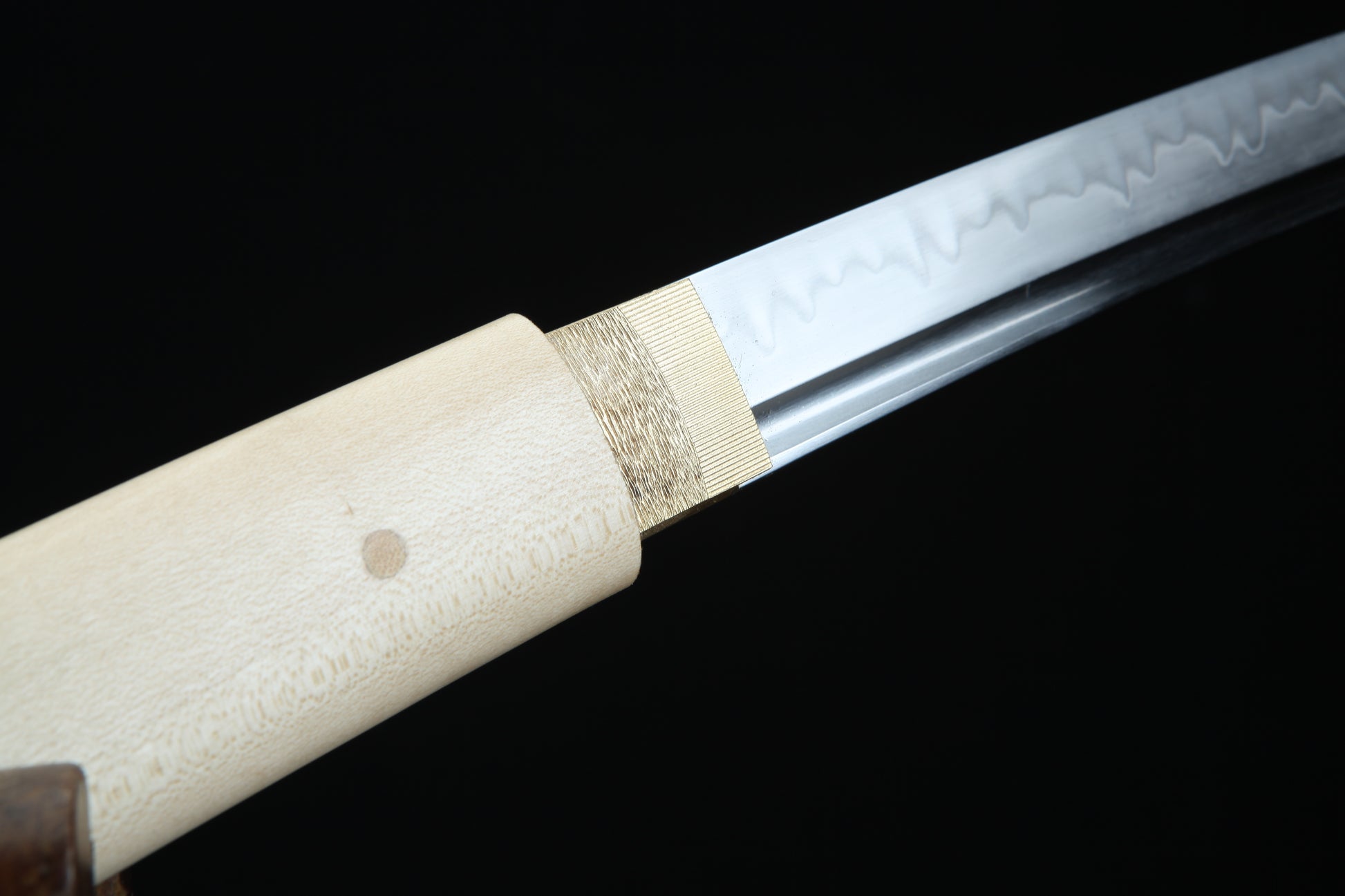 Close-up of a sword with a white handle on a black background