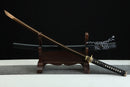 Sword with a black sheath on a wooden stand against a dark background