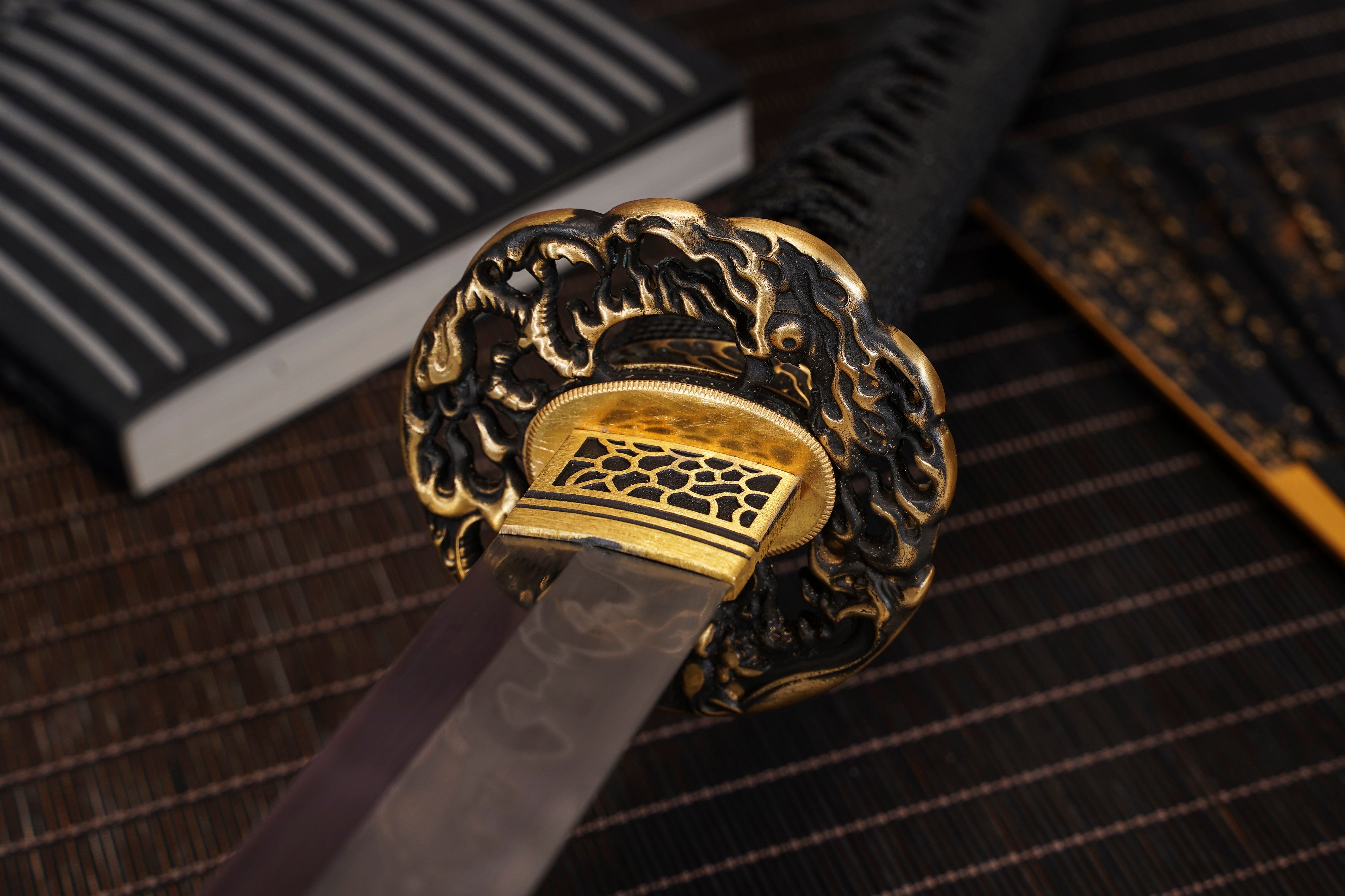 Close-up of the Moonswords Chi no Bara Katana's tsuba and clay-tempered T10 steel blade, showing the hamon line
