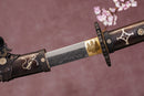 A close-up view of Moonswords Furin Kazan Katana with Hamon on the blade and intricate brown and gold designs on the handle.