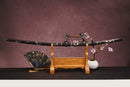 A close-up view of Moonswords Furin Kazan Katana, with a black handle and white accents, featuring intricate designs and patterns.