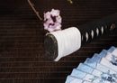 Close-up of Moonswords Ghost of Yotei katana handle with intricate designs on a textured surface.