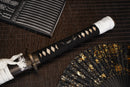 A close-up view of Moonswords Ghost of Yotei Katana with bronze guard, black handle and black shealth.