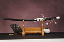 A close-up view of Moonswords Ghost of Yotei Katana, with a black handle and white accents, featuring intricate designs and patterns.