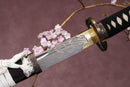 A close-up view of Moonswords Ghost of Yotei Katana with Hamon on the blade and intricate brown and gold designs on the handle.
