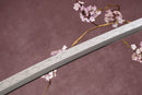A close-up view of a Clay-Tempered T10 Steel blade against a textured background.