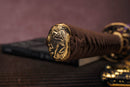 Close-up of Moonswords Hi No Ko katana handle with intricate designs on a textured surface.