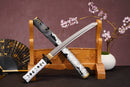 A close-up view of Moonswords Ghost of Tsushima Tanto, with a white handle and black accents, featuring intricate designs and patterns.