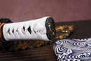 Close-up of Moonswords Ghost of Tsushima Tanto handle with intricate designs on a textured surface.