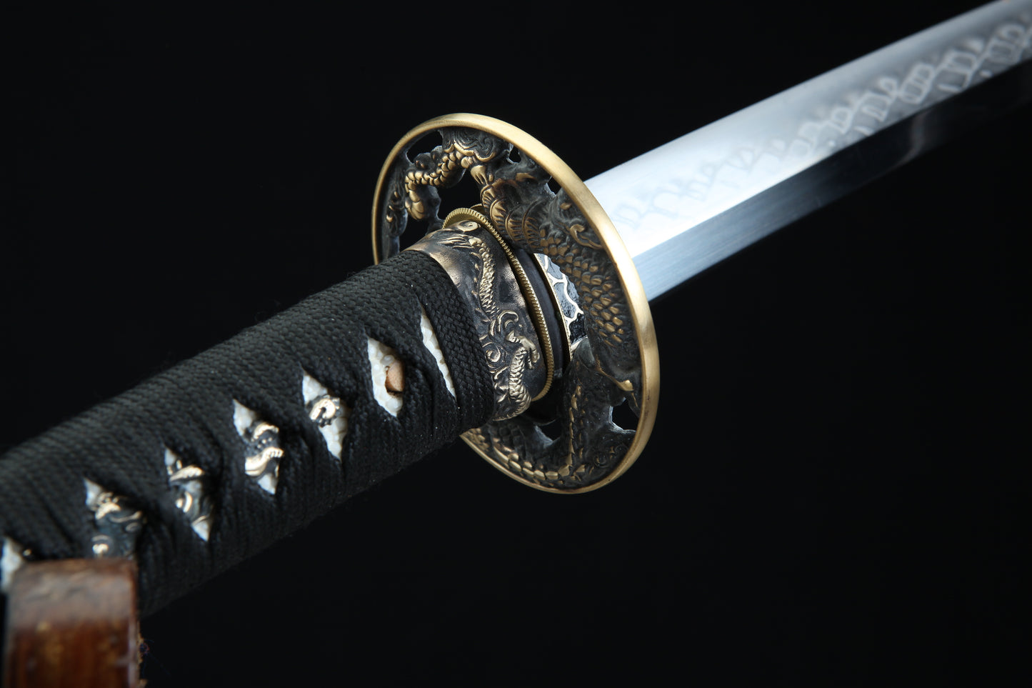 Close-up of a sword with a decorative hilt on a black background