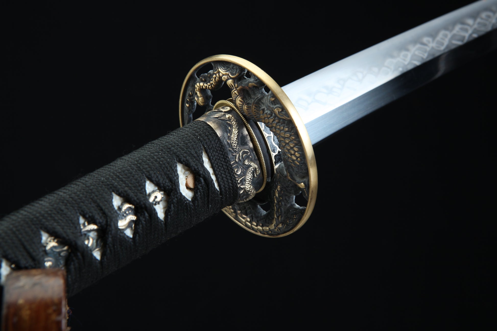 Close-up of a sword with a decorative hilt on a black background