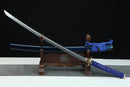 Sword with blue sheath on a wooden stand against a black background
