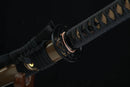 Close-up of a black sword sheath with intricate patterns on a dark background