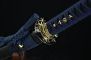 Close-up of a blue sword sheath with gold decorative elements on a black background