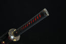 Sword handle with black grip and red accents on a dark background