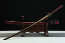 Sword with a red blade and black sheath on a wooden stand against a dark background