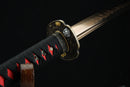 Close-up of a Japanese sword with a black and red handle on a dark background