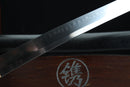 Sword blade with engraved text on a wooden surface