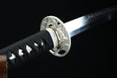 Close-up of a Japanese sword with a black handle and silver blade on a dark background
