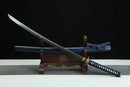 Sword with blue sheath on a wooden stand against a black background
