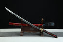 Sword with red sheath on a wooden stand against a black background