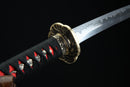 Close-up of a Japanese sword with a black and red handle on a black background