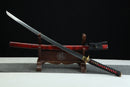 Sword with red and black handle on a wooden stand against a dark background