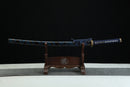 A blue and gold Japanese-style sword is displayed on a wooden stand against a black background.
