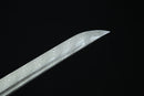 A close-up view of a knife with a distinctive, textured pattern on its blade against a dark background.