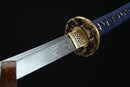 A close-up view of a sword with a decorative gold-colored blade and a blue handle, against a black background.
