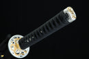 Close-up of a black sword handle with gold decorative elements on a black background