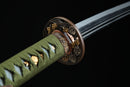 A photo of Moonswords Kyochiku Katana with a silver and gold-gilded bronze guard, is shown against a dark background.