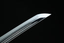 A close-up view of a Clay-tempered Tamahagane Steel blade against a dark background.