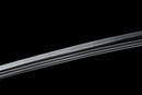 A close-up view of a clay-tempered Tamahagane steel blade against a black background